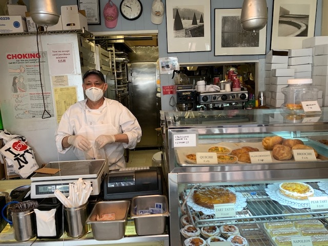 Pablo Valdez in a mask behind the counter at Patisserie Claude on West Fourth Street.