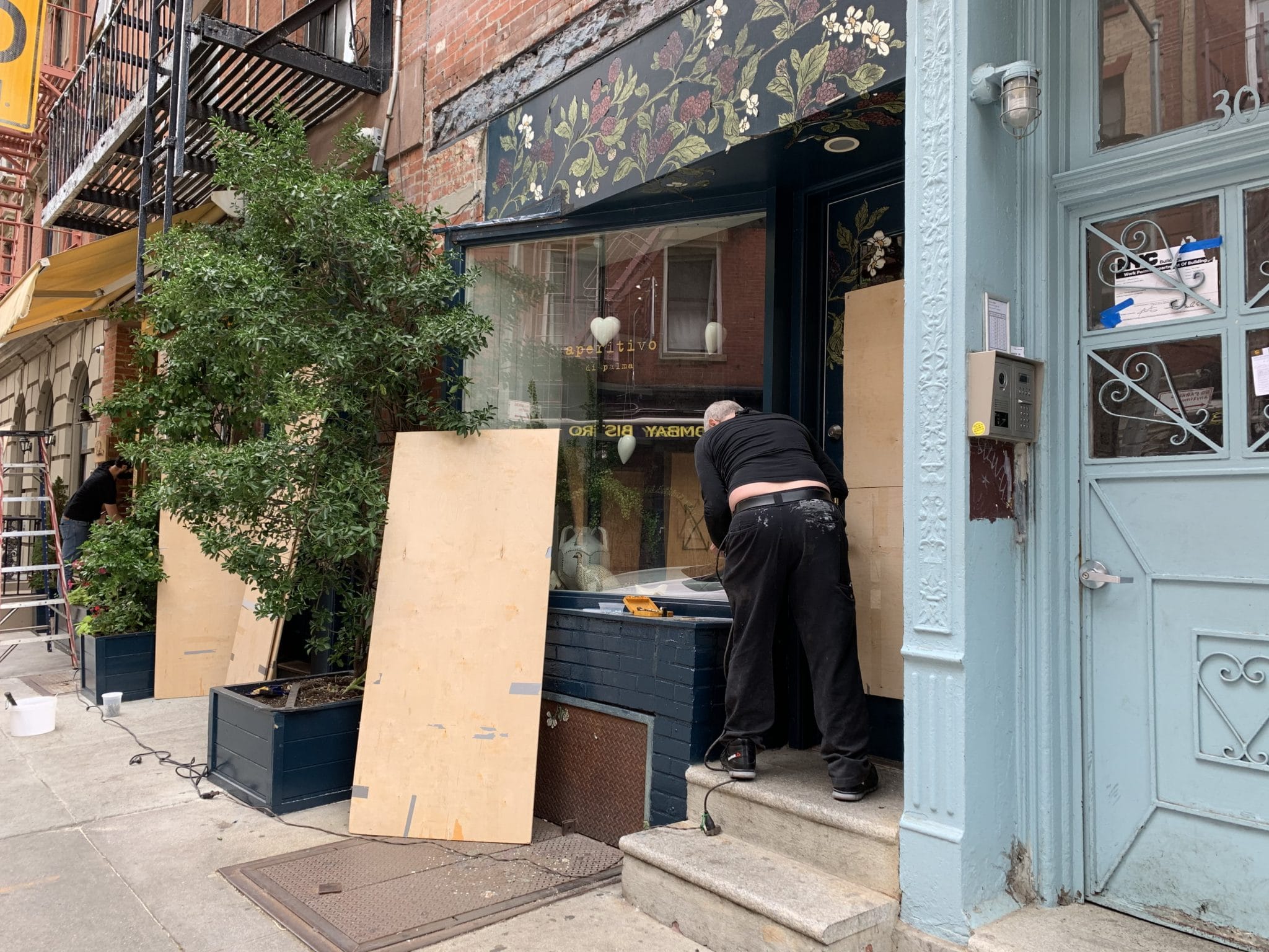 Worker boarding up a restaurant on Cornelia Street