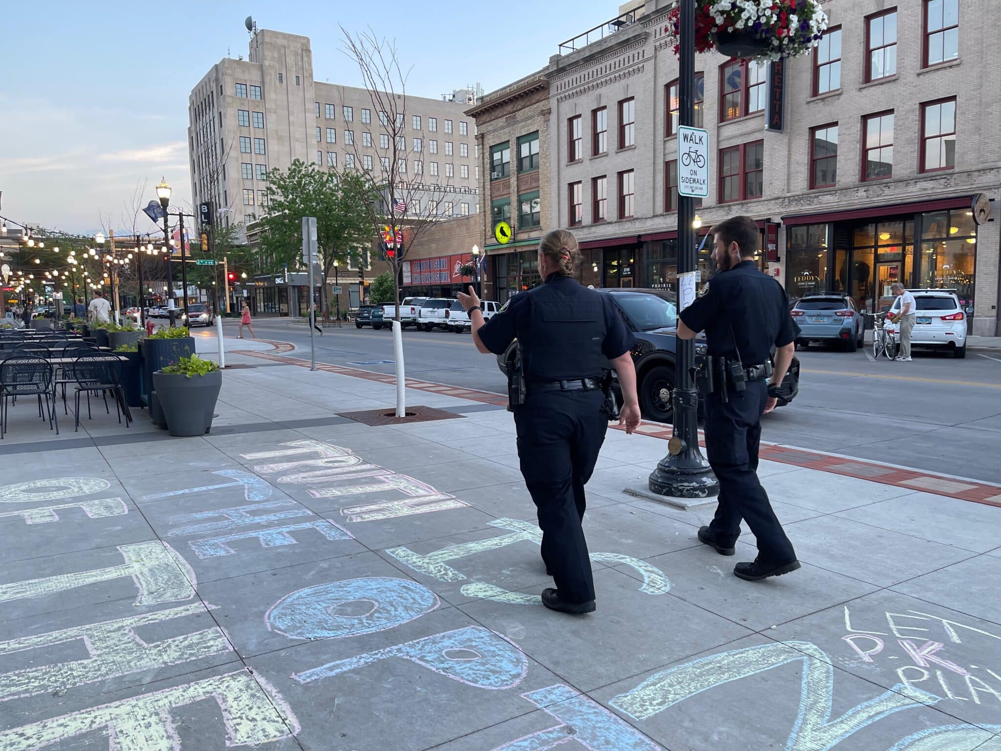 Two police office walking over chalked sidewalk in Fargo, North Dakota