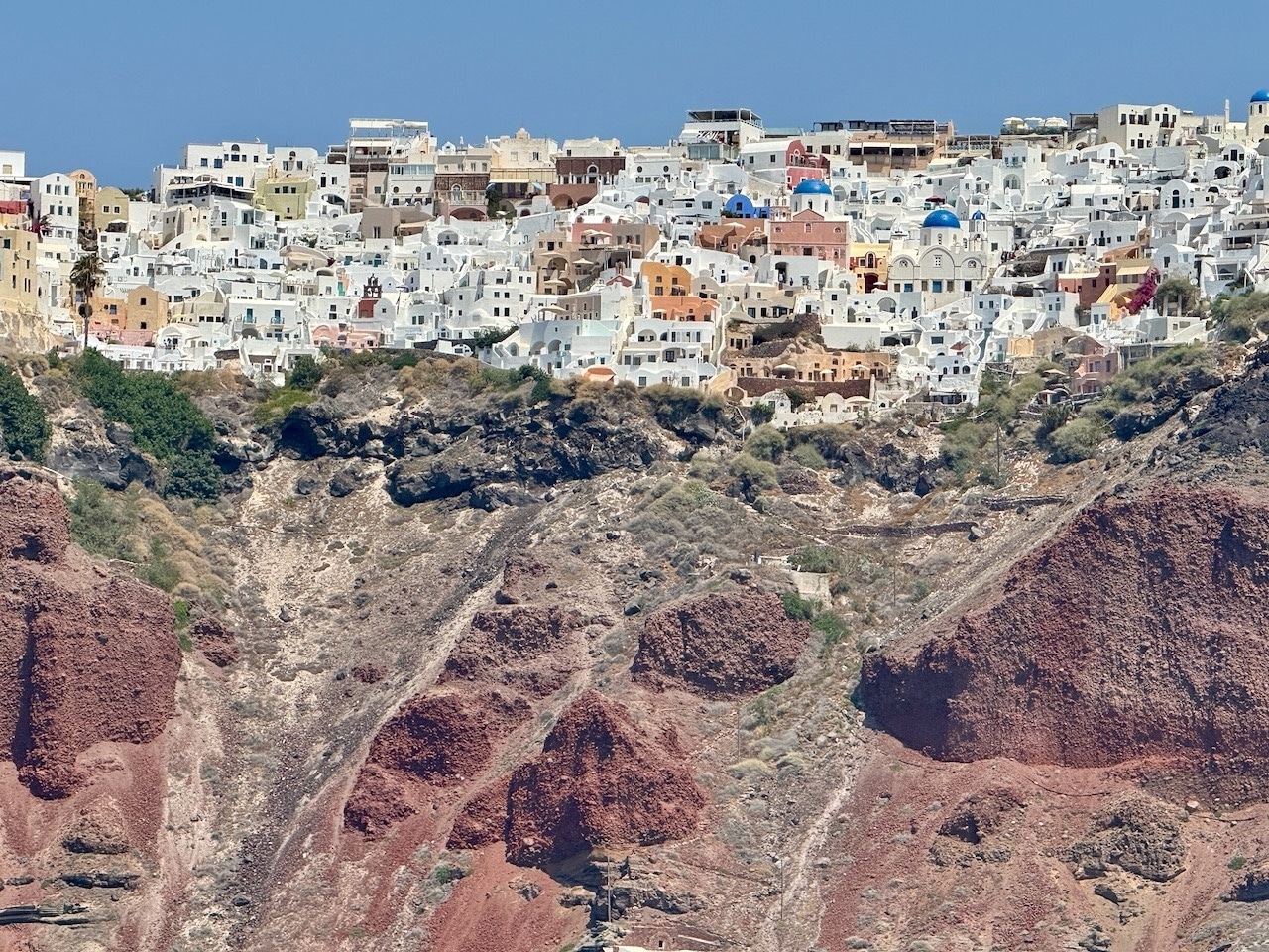 Santorini from the sea with blue-domed churches. Photo by ConsumerMojo.com